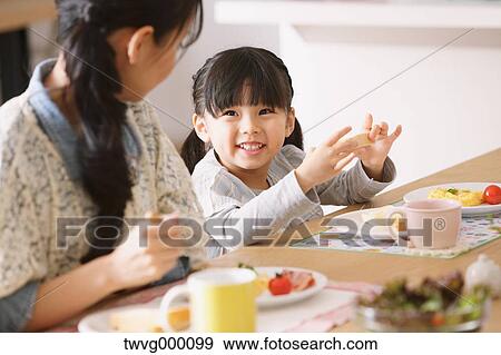 Young adult mother and daughter smiling at each other while having breakfast View Large Photo Image Stock Photo - Young adult mother and daughter smiling at each other while having breakfast. Fotosearch