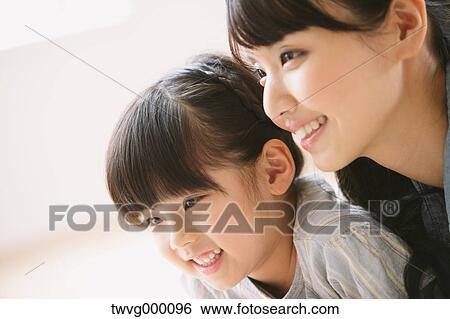Young adult mother and daughter smiling while looking away View Large Photo Image Stock Photograph - Young adult mother and daughter smiling while looking away. Fotosearch