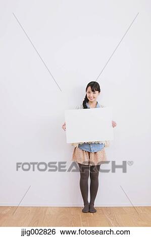 Young adult woman leaning against a white wall with whiteboard and smiling at camera View Large Photo Image Stock Photograph - Young adult woman leaning against a white wall with whiteboard and smiling at camera. Fotosearch