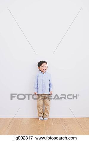Young boy leaning against a white wall View Large Photo Image Stock Photo - Young boy leaning against a white wall. Fotosearch