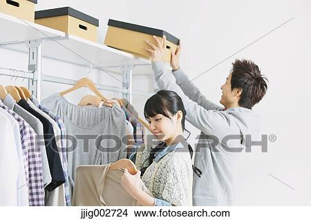 Young couple choosing clothes in a walk in closet View Large Photo Image Picture - Young couple choosing clothes in a walk in closet. Fotosearch