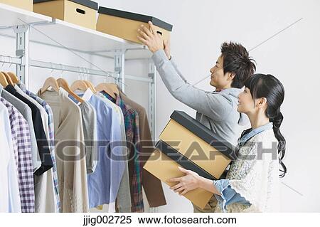 Young couple choosing clothes in a walk in closet View Large Photo Image Stock Photography - Young couple choosing clothes in a walk in closet. Fotosearch