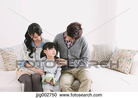 Stock Image - Young family relaxing on the sofa. Fotosearch