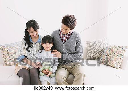 Young family relaxing on the sofa View Large Photo Image Stock Photo - Young family relaxing on the sofa. Fotosearch