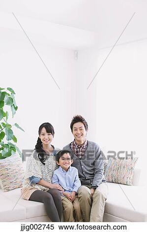 Young family relaxing on the sofa View Large Photo Image Stock Photography - Young family relaxing on the sofa. Fotosearch