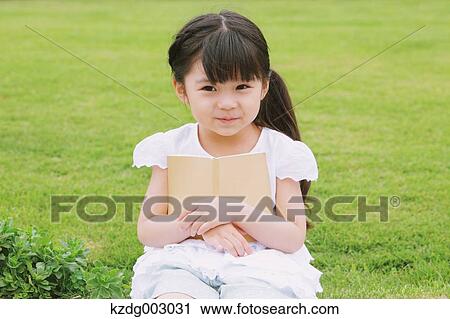 Stock Image - Young girl sitting with a book. Fotosearch