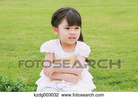 Stock Image - Young girl sitting with a book. Fotosearch