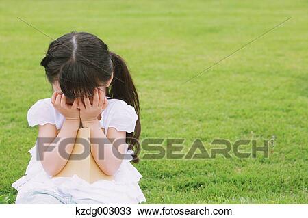Stock Image - Young girl sitting with a book. Fotosearch