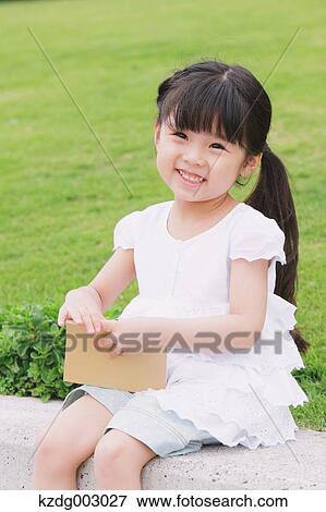 Stock Photo - Young girl sitting with a book. Fotosearch