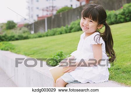 Stock Photo - Young girl sitting with a book. Fotosearch