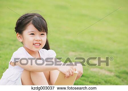 Stock Photo - Young girl sitting with a book. Fotosearch