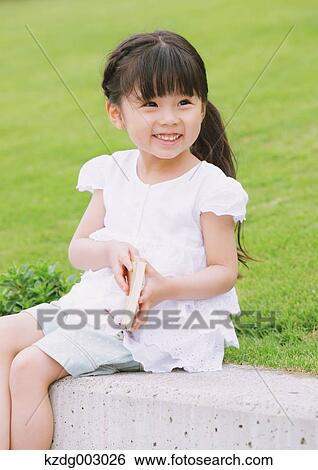 Young girl sitting with a book View Large Photo Image Stock Photograph - Young girl sitting with a book. Fotosearch