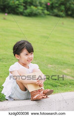 Stock Photograph - Young girl sitting with a book. Fotosearch