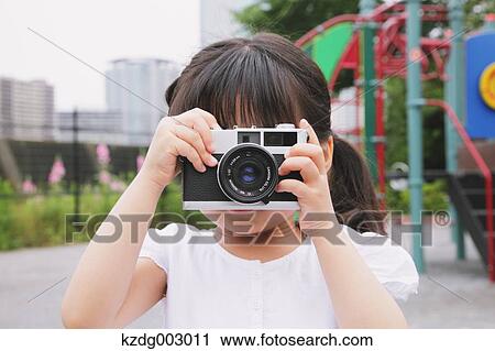 Stock Image - Young girl with camera. Fotosearch