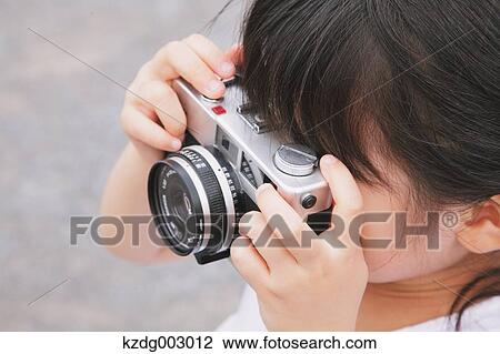 Stock Image - Young girl with camera. Fotosearch