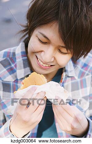 Picture - Young man eating a sandwich. Fotosearch