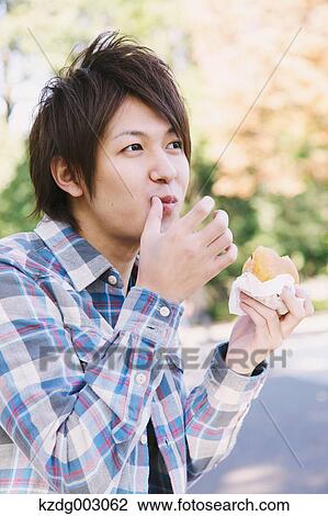 Young man eating a sandwich View Large Photo Image Stock Image - Young man eating a sandwich. Fotosearch