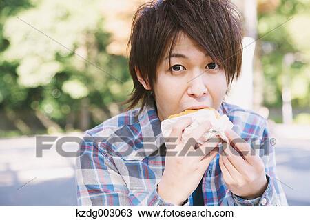 Young man eating a sandwich View Large Photo Image Stock Image - Young man eating a sandwich. Fotosearch