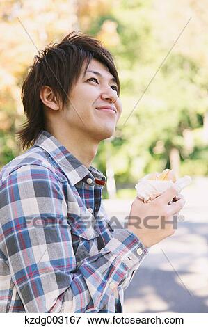 Young man eating a sandwich View Large Photo Image Stock Photo - Young man eating a sandwich. Fotosearch