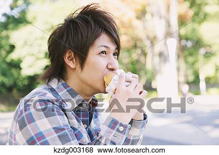 Young man eating a sandwich View Large Photo Image Stock Photo - Young man eating a sandwich. Fotosearch