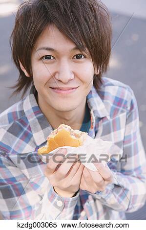 Young man eating a sandwich View Large Photo Image Stock Photography - Young man eating a sandwich. Fotosearch