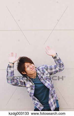 Stock Image - Young man hands on against a white wall. Fotosearch