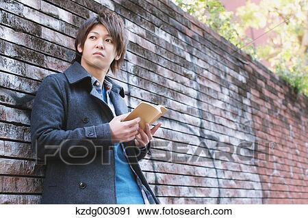 Stock Image - Young man holding a book. Fotosearch