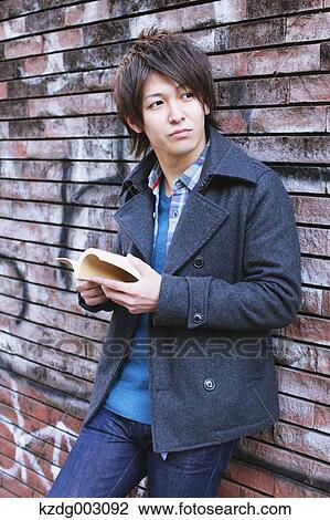 Stock Image - Young man holding a book. Fotosearch