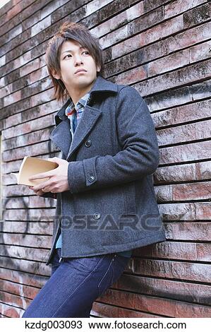Stock Image - Young man holding a book. Fotosearch