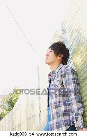 Picture - Young man leaning against a wall. Fotosearch