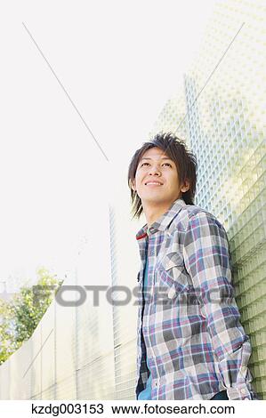 Young man leaning against a wall View Large Photo Image Stock Image - Young man leaning against a wall. Fotosearch