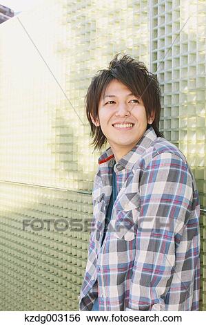 Young man leaning against a wall View Large Photo Image Stock Photograph - Young man leaning against a wall. Fotosearch