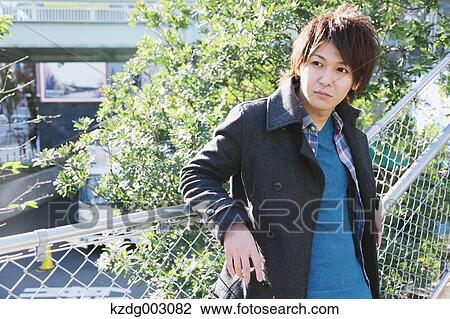 Young man leaning on a fence View Large Photo Image Stock Image - Young man leaning on a fence. Fotosearch