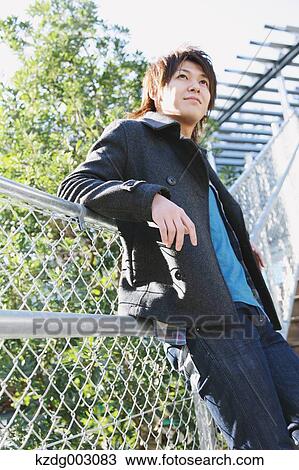 Stock Image - Young man leaning on a fence. Fotosearch