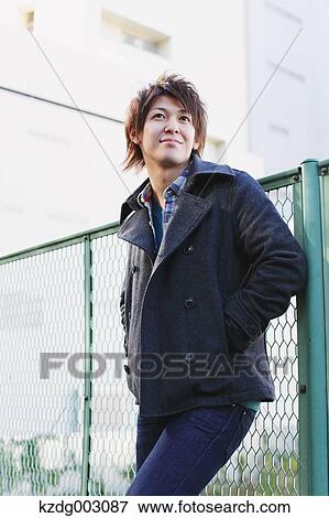 Stock Photo - Young man leaning on a fence. Fotosearch
