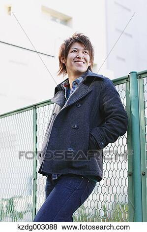 Young man leaning on a fence View Large Photo Image Stock Photo - Young man leaning on a fence. Fotosearch