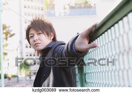 Stock Photo - Young man leaning on a fence. Fotosearch