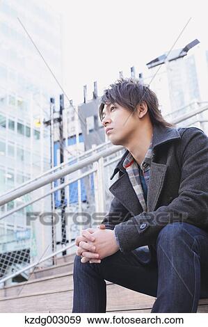 Young man sitting on the stairs View Large Photo Image Stock Photo - Young man sitting on the stairs. Fotosearch