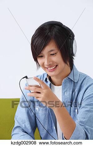 Young man with earphones on the sofa View Large Photo Image Stock Photo - Young man with earphones on the sofa. Fotosearch