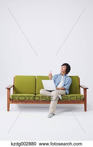 Stock Image - Young man with laptop on the sofa. Fotosearch