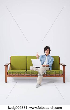 Stock Image - Young man with laptop on the sofa. Fotosearch