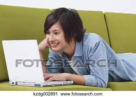 Young man with laptop on the sofa View Large Photo Image Stock Image - Young man with laptop on the sofa. Fotosearch