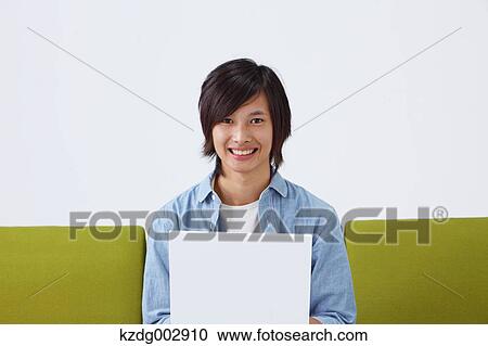 Young man with laptop on the sofa View Large Photo Image Stock Image - Young man with laptop on the sofa. Fotosearch