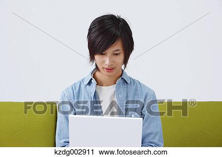 Young man with laptop on the sofa View Large Photo Image Stock Image - Young man with laptop on the sofa. Fotosearch