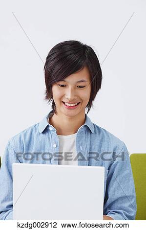 Young man with laptop on the sofa View Large Photo Image Stock Image - Young man with laptop on the sofa. Fotosearch