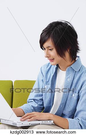 Stock Image - Young man with laptop on the sofa. Fotosearch
