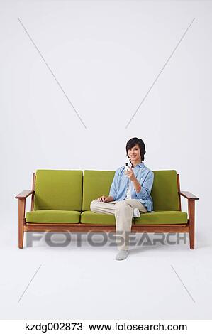 Stock Image - Young man with phone on the sofa. Fotosearch