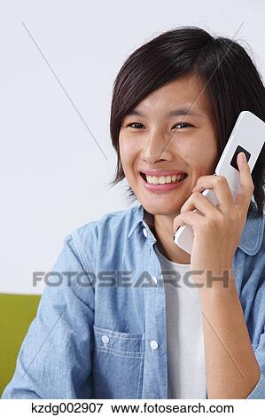 Stock Photo - Young man with phone on the sofa. Fotosearch