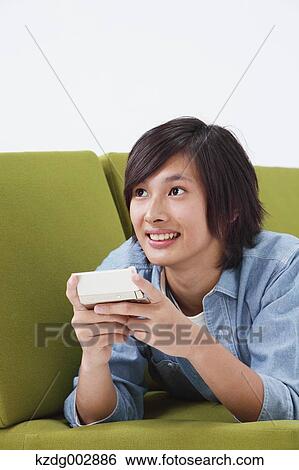 Young man with phone on the sofa View Large Photo Image Stock Photograph - Young man with phone on the sofa. Fotosearch