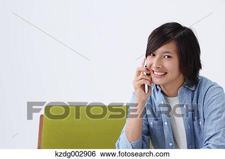 Stock Photograph - Young man with phone on the sofa. Fotosearch